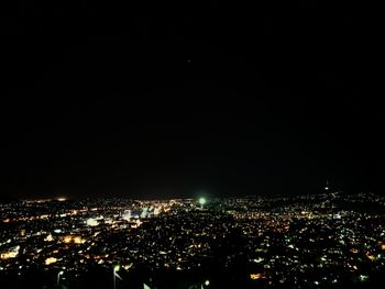 Illuminated cityscape against clear sky at night