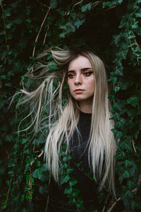 Beautiful young woman looking away while standing by plants