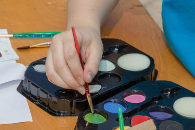 Cropped hand of girl using palette