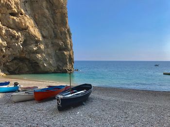 Boats moored on sea shore against sky