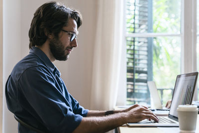 Businessman sitting in office, working at laptop