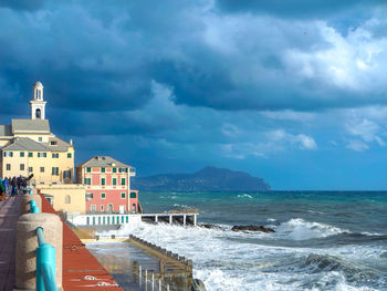 Scenic view of beach by buildings against sky