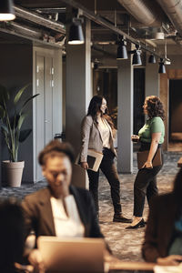 Multiracial business colleagues talking to each other while standing in office