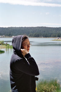 Young man looking at lake against sky