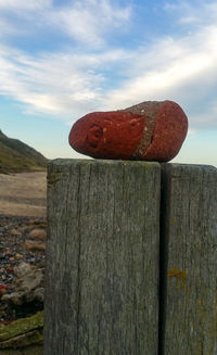 Close-up of wooden post on fence by land against sky