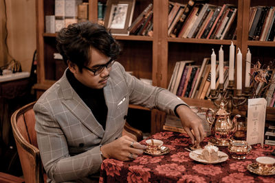 Young man looking away while sitting on table