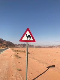 Road sign in desert against clear sky