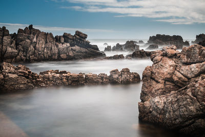 A long exposure of rocky coastline with water motion blurred in silky look