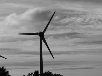 Low angle view of wind turbine against cloudy sky