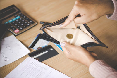 Cropped hands of businesswoman holding wallet at desk in office