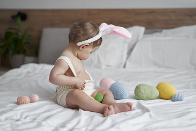 Side view of girl sitting on bed