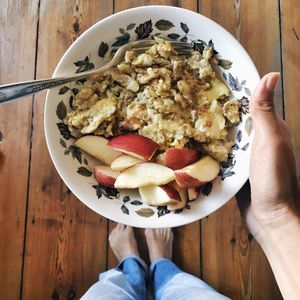 Low section of man holding breakfast in bowl over floorboard