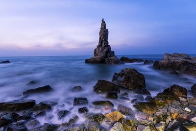 Scenic view of rocks in sea against sky during sunset