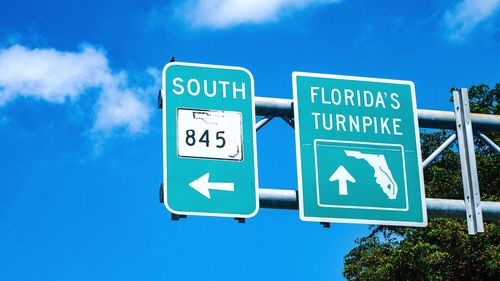 Low angle view of road sign against blue sky