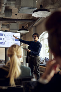 Businessman gesturing while explaining to colleague during meeting