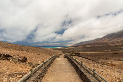 Scenic view of road leading towards mountains against sky