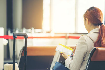 Side view of woman using mobile phone while sitting in cafe