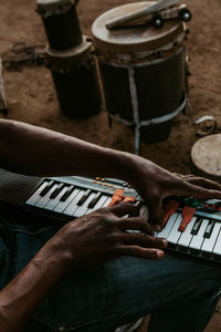 Midsection of man playing piano while sitting outdoors