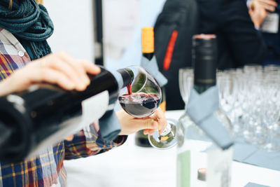 Midsection of man pouring wine in glass on table