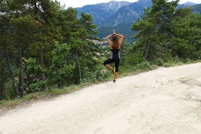 Full length rear view of woman meditating while standing on field