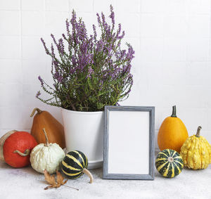 Picture frame and pumpkin decor on the table over white tile background. fall season greeting card.