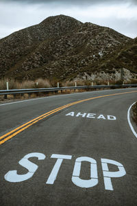 Text on road by mountain against sky
