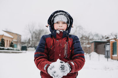 Close up outdoor winter portrait of boy playing snowballs. authentic, real, candid portrait of cute