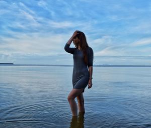 Young woman standing on beach against sky