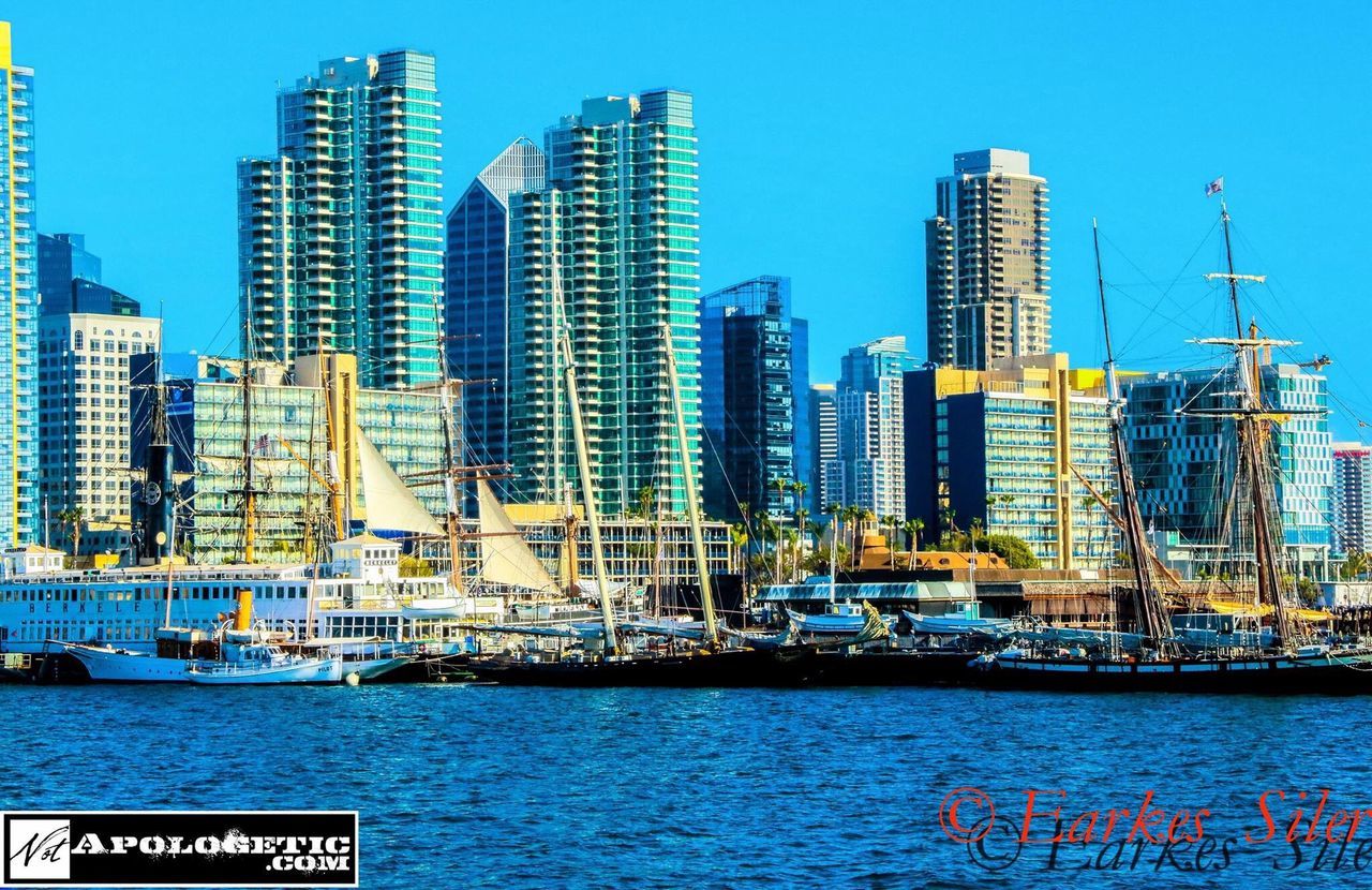 city, architecture, building exterior, skyscraper, blue, clear sky, modern, built structure, travel destinations, sea, no people, outdoors, growth, waterfront, tower, urban skyline, day, low angle view, water, cityscape, development, nautical vessel, tall, sky