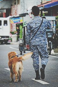 Rear view of woman with dog walking on road