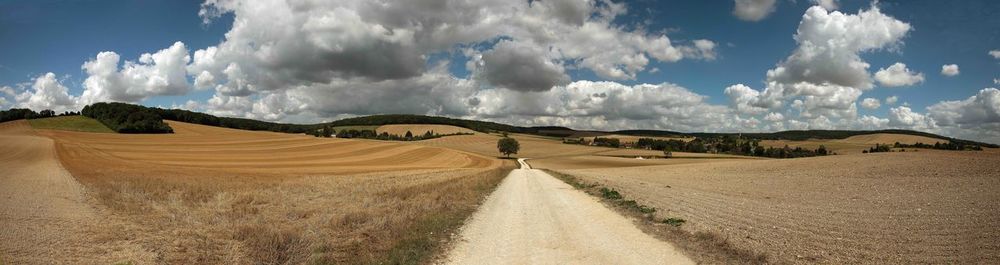 Panoramic shot of dirt road against sky