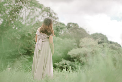 Rear view of woman standing on land in forest