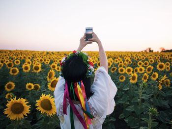 Rear view of girl photographing on field