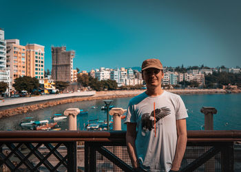 Young man standing by railing against clear sky