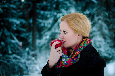 Woman holding apple while standing outdoors