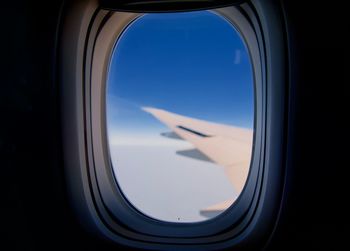Aircraft wing seen through glass window against sky 
