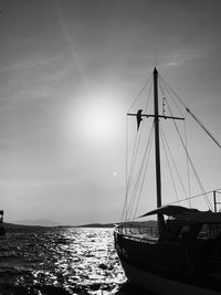 Sailboat moored on sea against sky during sunset