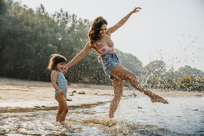 Mother and daughter enjoying in water at beach