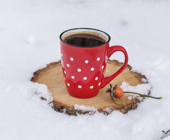 Close-up of coffee cup on wood amidst snow