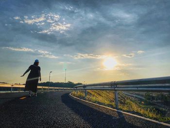 Rear view of man on road against sky during sunset
