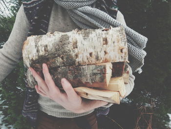 Midsection of woman holding firewood