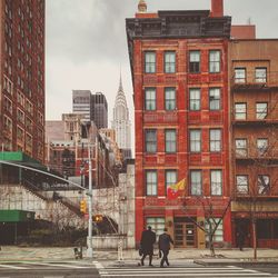 People walking on street against buildings in city