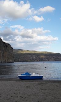 Boat moored on sea shore against sky