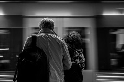 Rear view of man and woman standing at railroad station