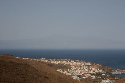 Aerial view of city by sea against sky