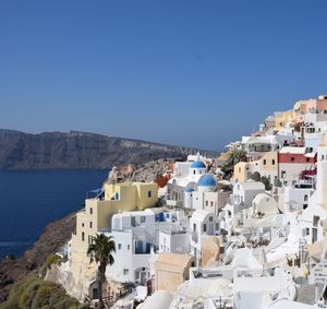 Townscape by sea against clear blue sky