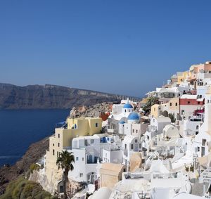 Townscape by sea against clear blue sky