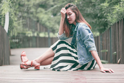 Full length of young woman sitting outdoors