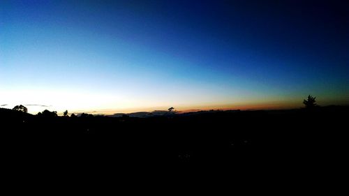 Silhouette landscape against clear sky at sunset