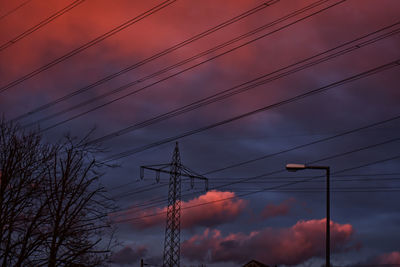 Low angle view of power lines against cloudy sky